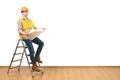 The engineer with a paper standing on the ladder on the white wall background Photo