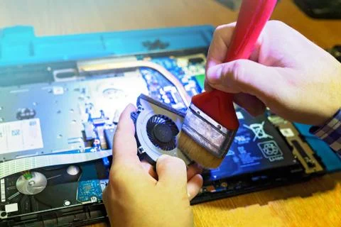 Engineer performs mechanical cleaning of laptop cooler Stock Photos