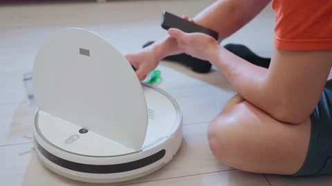 Engineer Picks Up Screw While Repairing Robot Vacuum on Floor Stock Footage 320019017