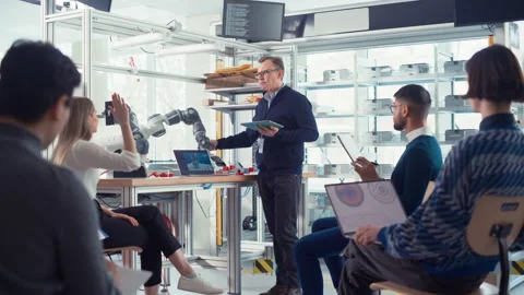 Engineer Presents Robot Arm To Startup Workers Stock Footage 187564936