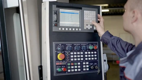 Engineer is programing cnc machine in production workshop, pressing buttons and Stock Footage 95090311