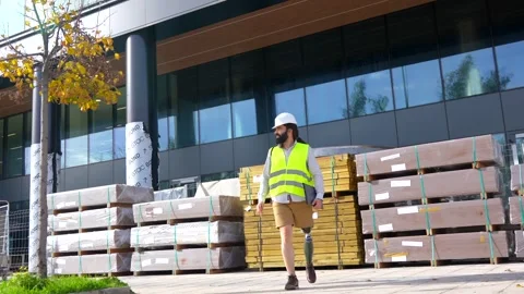 Engineer with prosthetic leg walking along the street Stock Footage 260558736