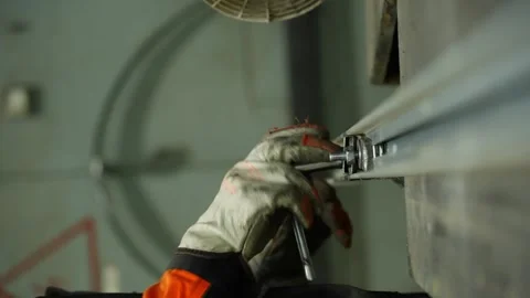 An engineer in protective gear and gloves unscrews bolts with a special wrench. Video stock 343530617