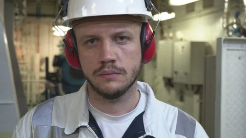 Engineer in a protective helmet with a sad face standing in the engine room Stock Footage 116677009