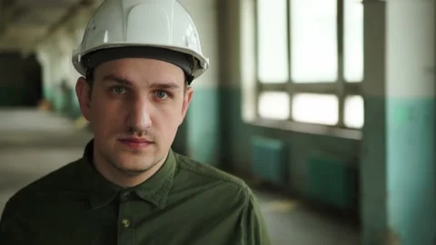 An engineer puts a safety helmet on his head on site. Looks into the camera Stock Footage 152679755