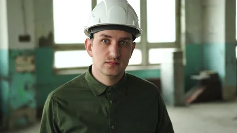 An engineer puts a safety helmet on his head on site. Looks into the camera Stock Footage 152679775