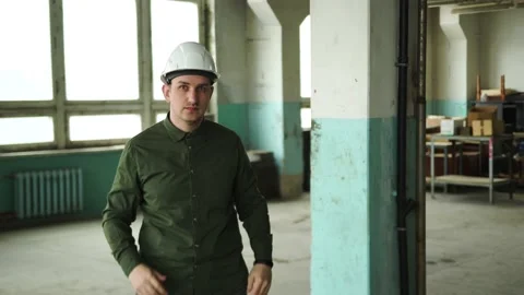 An engineer puts a safety helmet on his head on site. Looks into the camera Stock Footage 152679834