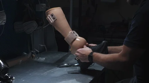 An engineer puts on sneakers on a prosthetic leg. Inserts the prosthesis into Video stock 120156301