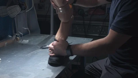 An engineer puts on sneakers on a prosthetic leg. Inserts the prosthesis into Stock Footage 120156859
