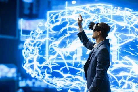 Engineer raises hand while wearing VR headset next to AI visualization Stock Photos