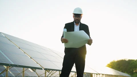 Engineer reading blueprints at solar farm during sunset Stock Footage 314408412