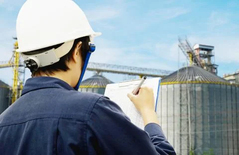 Engineer is recording data with power plant background Stock Photos
