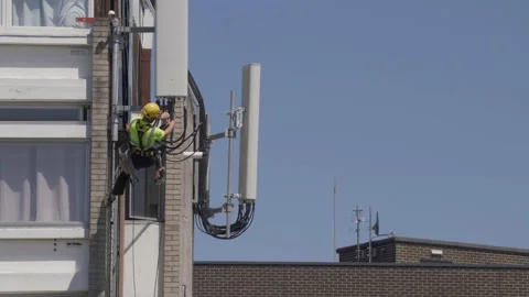 An Engineer repairing cables on a 5G Mast on a building Stock Footage 130863693