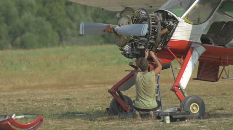 The engineer repairing the engine of the plane on the glade Stock Footage 56182720