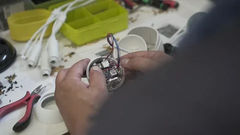 An engineer repairs electronics in a workshop, holding a disassembled white CCTV Stock Footage 142725693