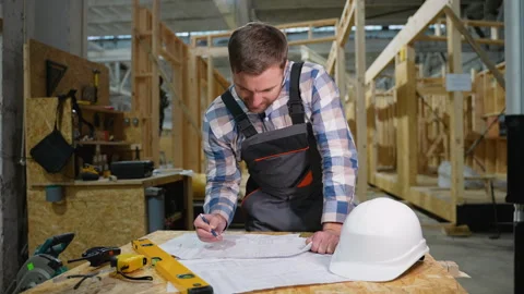 Engineer reviewing blueprints at modular house factory Video stock 301827230