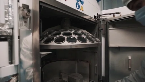 Engineer in robe and rubber gloves operates parts inside oven in laboratory Stock Footage
