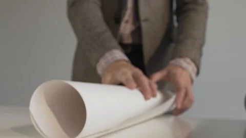 Engineer rolls whatman paper on a white table Stock Footage 124209700