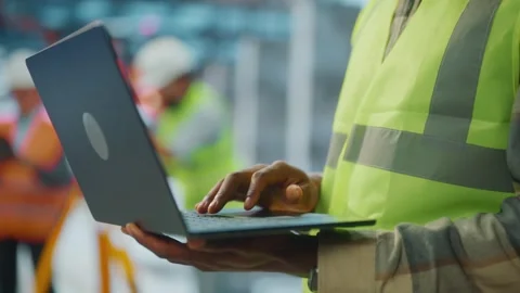 Engineer in safety vest using laptop on construction site close up. Stock Footage 337411707