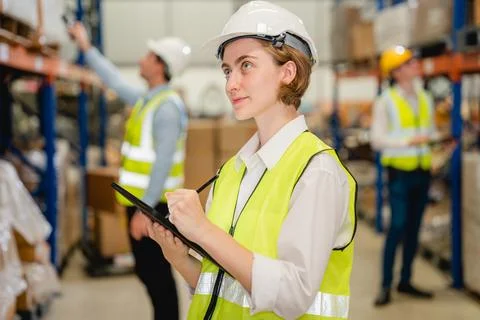 Engineer with safety vest using tablet checking goods on shelves 스톡 사진
