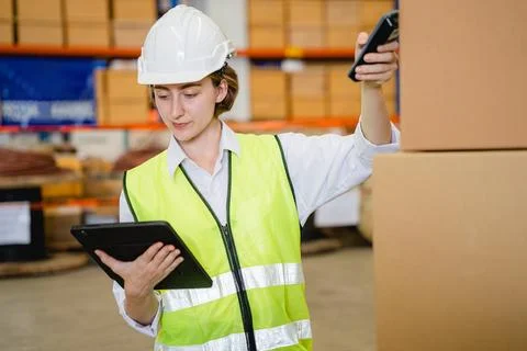 Engineer with safety vest using tablet checking goods on shelves Stock Photos