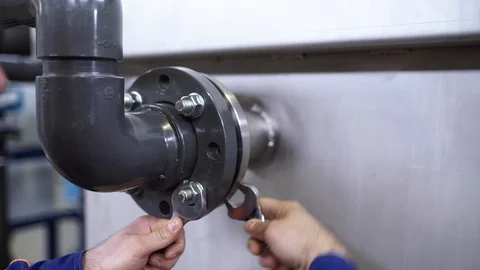 The engineer screws the bolts onto the flange connection. Stock Footage 93207789