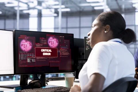 Engineer in server hub investigating breach alerts, working to protect equipment Stock Photos