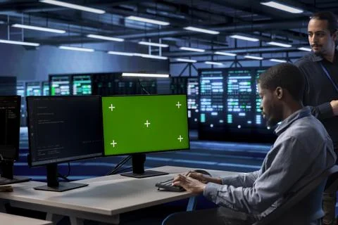Engineer in server hub using green screen computer to find misconfigurations Stock Photos