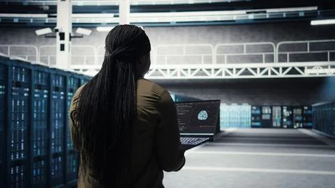 Engineer in server hub using laptop to upgrade rigs using AI deep learning Stock Photos