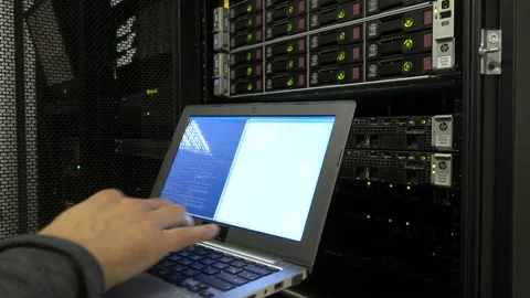 Engineer in the server room with a laptop on the background of hard drives. Video stock 95651459