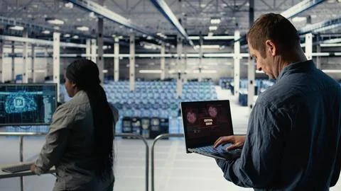 Engineer in server room receives critical error popup on laptop screen Stock Photos
