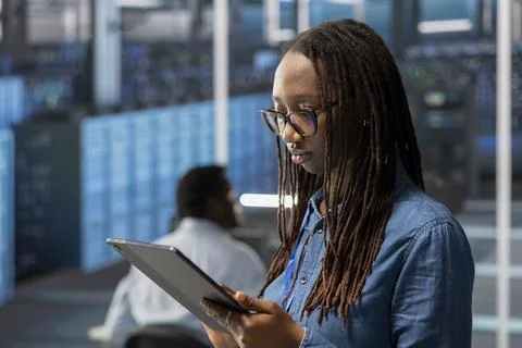 Engineer in server room using tablet to implement data backup solutions Stock Photos