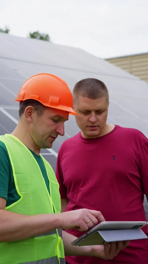 Engineer sets up solar power plant and shows how to use it to man on tablet. Stock Footage 313234904