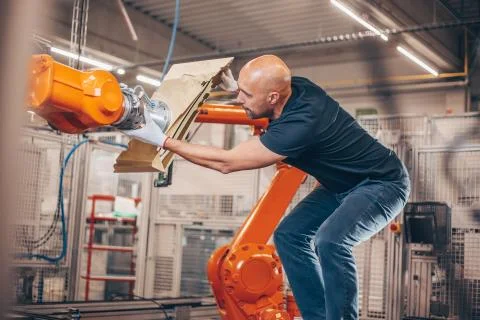 Engineer setting up automatic robot arm for production in automotive, industry Stock Photos