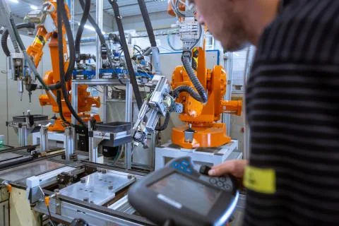 Engineer setting up automatic robot arms in smart factory, automotive industry 库存照片