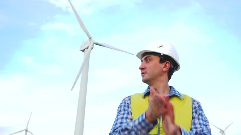 Engineer shakes off dust from hands after working on wind turbines ecological Stock Footage 137970015