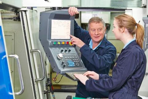 Engineer Showing Apprentice How to Use Computerized Cutting Machine Stock Photos