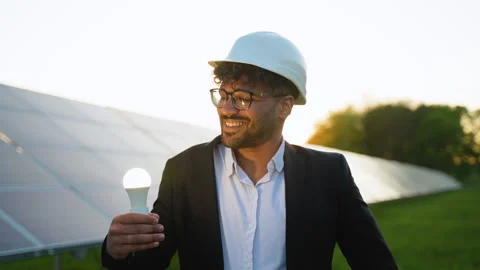 Engineer showing light bulb in solar panel farm at sunset Video stock 314410200