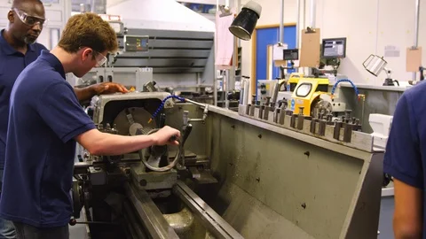 Engineer Showing Teenage Apprentice How To Use Lathe Stock Footage 86603675