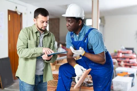 Engineer shows the estimate to a builder, explaining the working moments Stock Photos