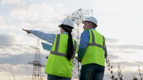 Engineer shows power transmission lines to inspector with tablet at dusk Stock Footage 264698740