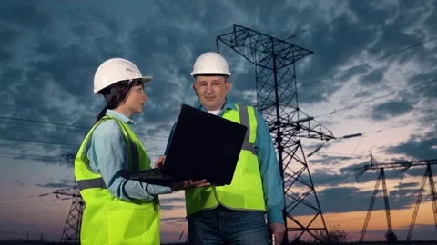 Engineer shows project on laptop to taskmaster by power transmission lines Stock Footage 253672018