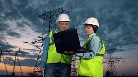 Engineer shows project on laptop to taskmaster by power transmission lines Stock Footage 254925551
