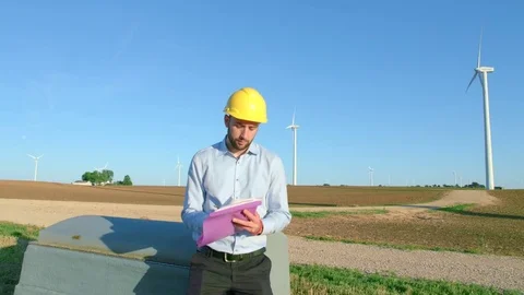 The engineer sits on the background of the windmills and takes notes in the Stock-Footage 76577106