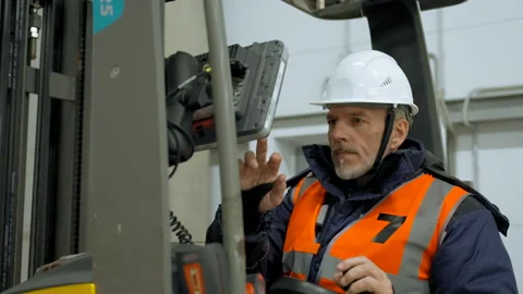 Engineer sits in forklift cabin pushing button on monitor Stock Footage 205816474