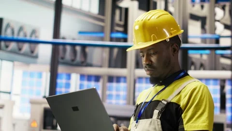 Engineer in smart factory does maintenance using laptop software, analyzing data Stock Footage 308716596
