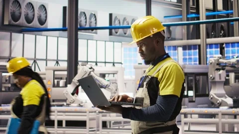 Engineer in smart factory does maintenance using laptop software, analyzing data Stock Footage 308721986