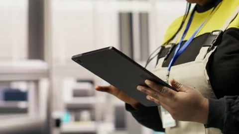 Engineer in smart factory oversees robotic assembly lines using tablet app Stock Footage 307361085