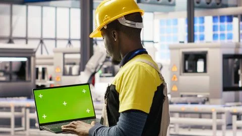 Engineer in smart factory using green screen laptop to analyze IoT sensors data 写真素材