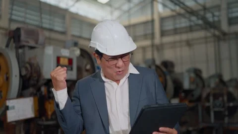 Engineer smiles, holding tablet, standing in factory Vídeos de archivo 346153085